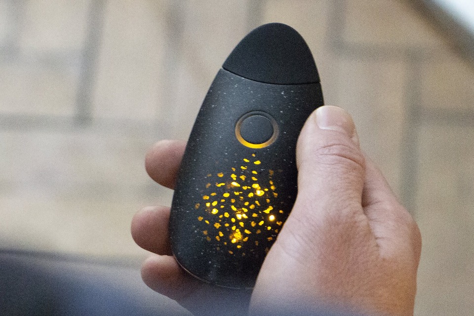 A hand holding the prototype, which has an amber glowing lights emitting through the surface like embers